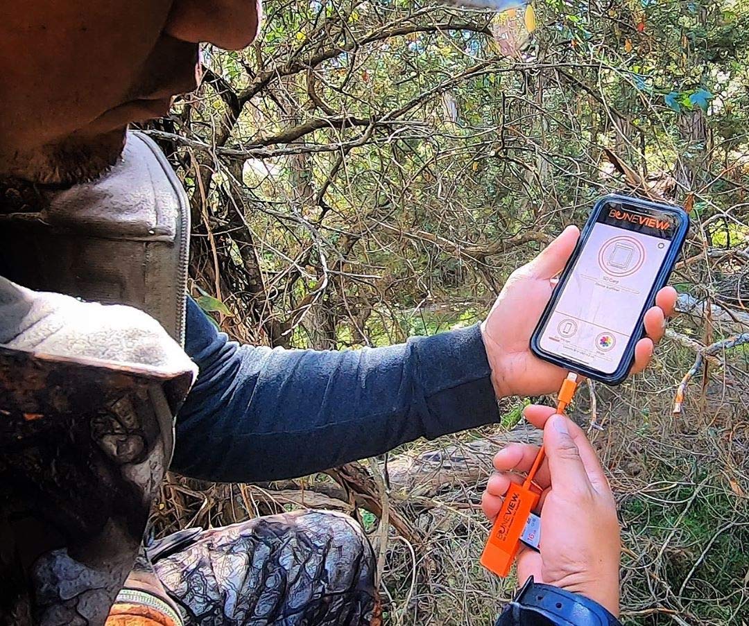 Deer hunter using BoneView SD Card Reader to check trail camera memory card on their Apple or Android smartphones using the BoneView custom App to download pictures and videos to their phone.